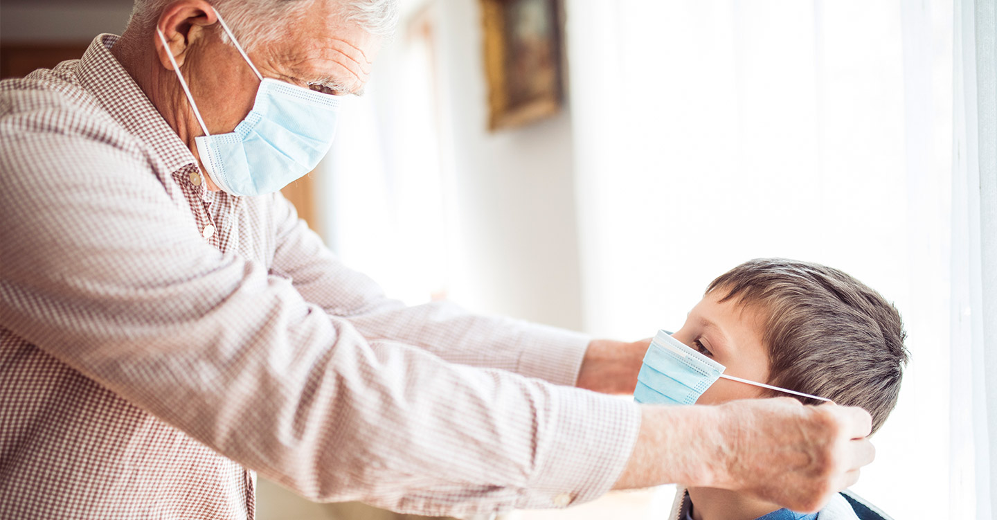 Gentleman placing surgical mask on a young child